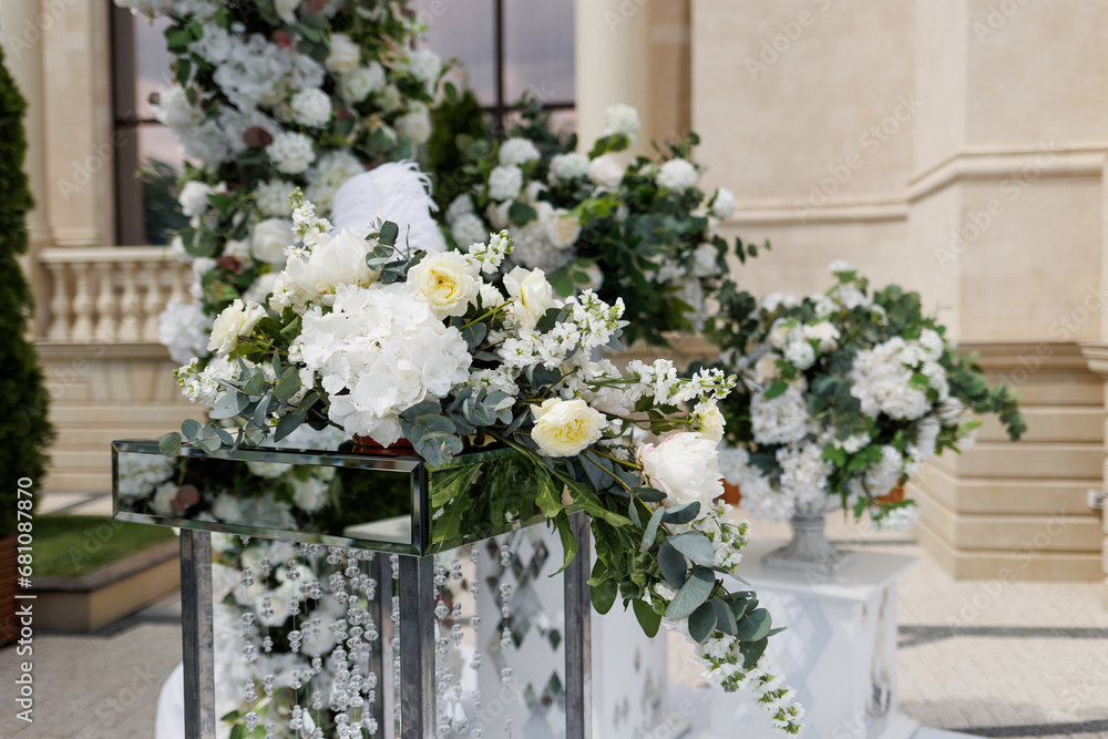 Close up of a table decorated with fresh white and yellow flowers for painting the newlyweds against the backdrop of the arch. Wedding concept