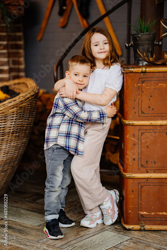 Little brother and sister hugging in the interior of a country house.