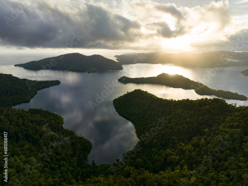 Low, sunlit clouds drift across the island of Batanta in Raja Ampat, Indonesia, at dawn. This area is known as the heart of the Coral Triangle due to its incredibly high marine biodiversity. photo