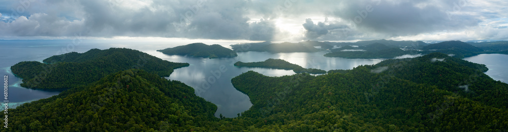 Low, sunlit clouds drift across the island of Batanta in Raja Ampat, Indonesia, at dawn. This area is known as the heart of the Coral Triangle due to its incredibly high marine biodiversity.