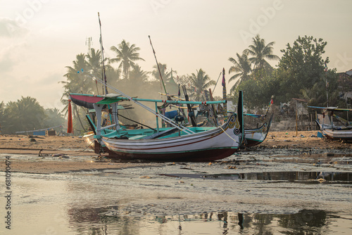 Fishing boats are stranded on the beach because sea water recedes in the morning photo