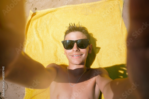 Teenage boy lying on the towel on a fabulous day at the beach.