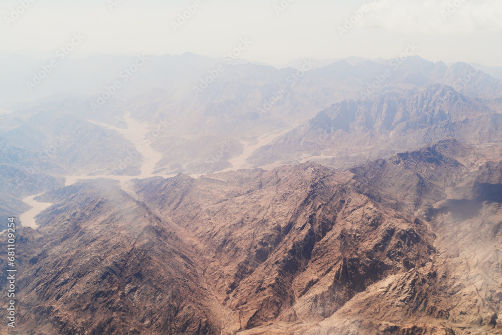 Aerial shot of arid mountains with a dry riverbed snaking through. Top view wallpaper.