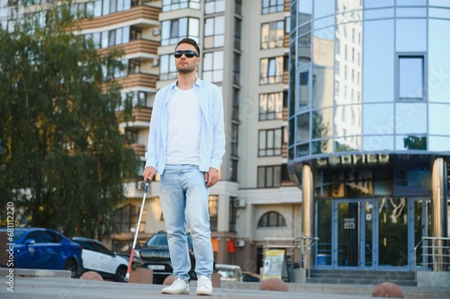 Young handsome blinded man walking with stick in town © Serhii