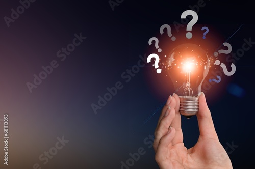 Businessman hand holding glowing lamp lightbulb with question mark photo