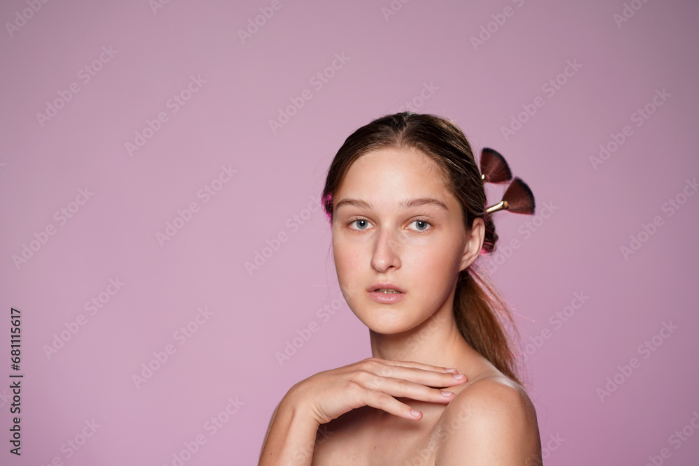 Portrait of young seminude woman in studio on pink background in pink neon light close up. Womans hair is pinned up with makeup brushes. Beauty, cosmetology, care. Portrait of young seminude woman in studio on pink background in pink neon light close up. Womans hair is pinned up with makeup brushes. Beauty, cosmetology, care.
