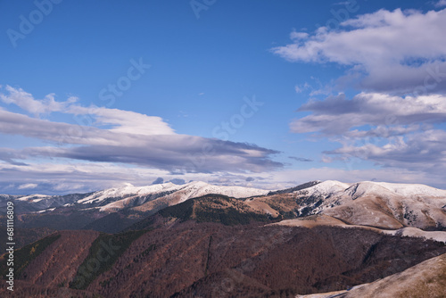 Scenic winter in the mountains with the first snowfall. A snowy landscape in the mountains during the winter season. Tops of winter mountains. Winter travel. Carpathian Mountains in Romania.