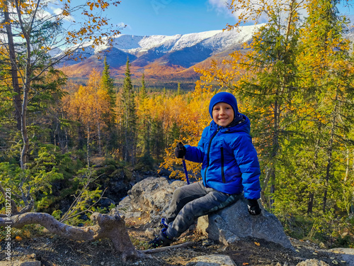 A boy on the background of an autumn Arctic landscape in the Khibiny mountains. Kirovsk, Kola Peninsula, Polar Russia. Autumn colorful forest in the Arctic, mountain hikes and adventures. photo