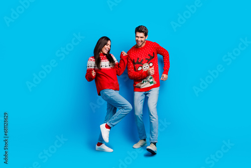 Full size photo of pretty young lovers dance have fun discotheque wear x-mas ornament red sweaters isolated on blue color background