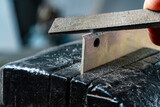 Craftsman works on small piece of metal with metal file gripped in vise on workbench table in garage workshop, do it yourself concept, closeup