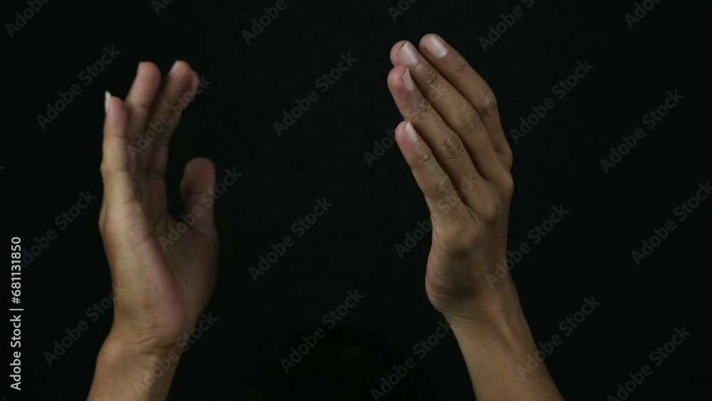 Male hands clapping against a black background.