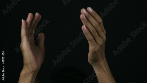 Male hands clapping against a black background.