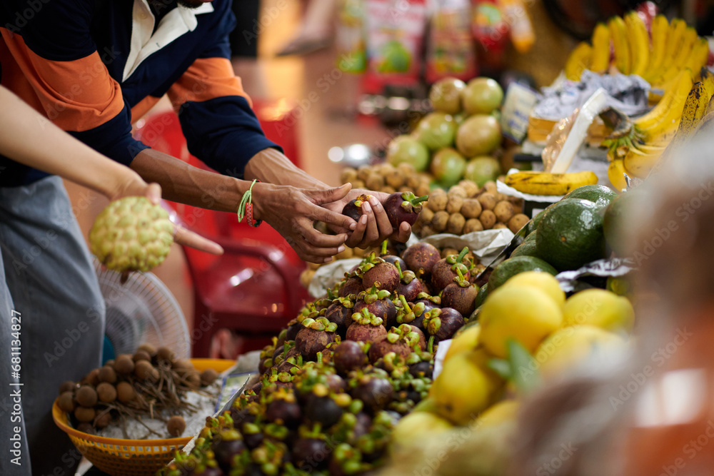 Hands of customer buying mangosteen fruits at local market - obrazy, fototapety, plakaty 