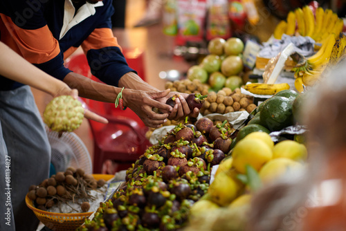 Hands of customer buying mangosteen fruits at local market photo