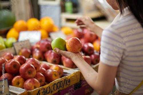 Young woman buying fresh organic fruits at local market photo