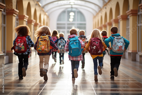 Elementary school children, with multi-colored backpacks, run in the school, rear view