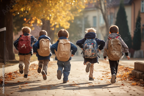 Elementary school children, with multi-colored backpacks, run in the school, rear view