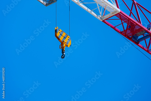 The yellow hook of a crane on a blue sky background. Personal growth concept.	