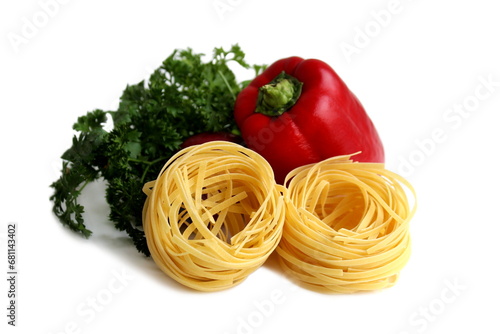 On a white background lies pasta in the form of a nest with vegetables.