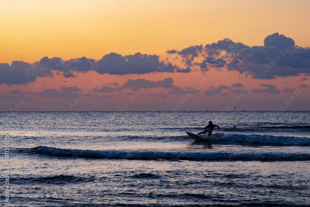 Obraz premium 日の出の中サーフィンをする人