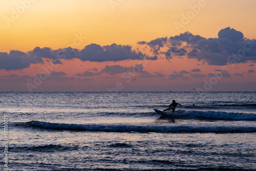 日の出の中サーフィンをする人 © syu