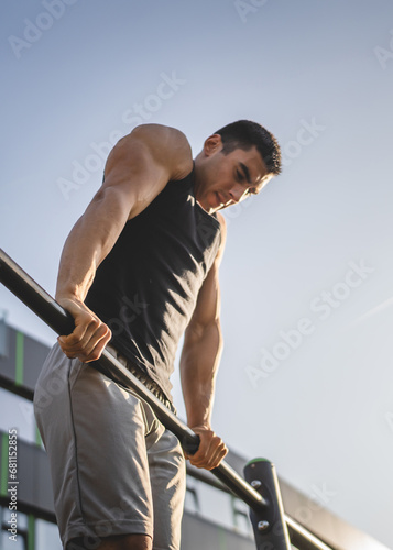 Картината върху платно One man muscular male athlete training pull ups outdoor in sunny day