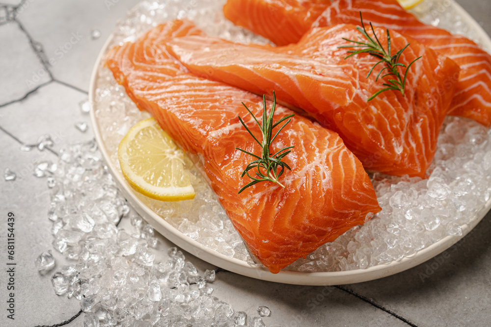 Salmon. Fresh raw salmon fish fillet with ice, lemon and herbs on gray background Salmon. Fresh raw salmon fish fillet with ice, lemon and herbs on gray background