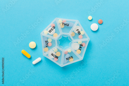 Tableau sur toile Daily pill organizer with medications on color background, top view