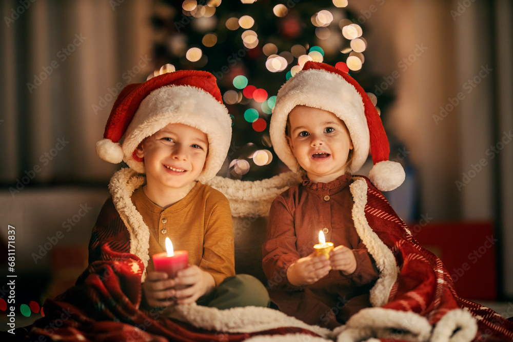 Portrait of a jolly children holding candles and smiling at the camera on christmas eve at home. Portrait of a jolly children holding candles and smiling at the camera on christmas eve at home.