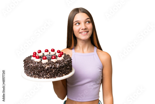 Teenager caucasian girl holding birthday cake over isolated background looking up while smiling
