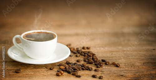 White cup with hot coffee and coffee beans on rustic wooden background