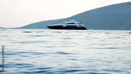 Luxurious motor yacht swimming through calm sea waves at sunset. Holiday, summer vacation and tourism