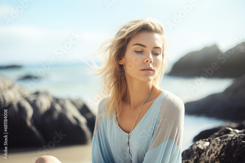 Coastal serenity: a young woman meditates on a seashore rock, practicing mindfulness and focused breathing for mental well-being—a breathwork concept embracing nature's calming influence © Martin