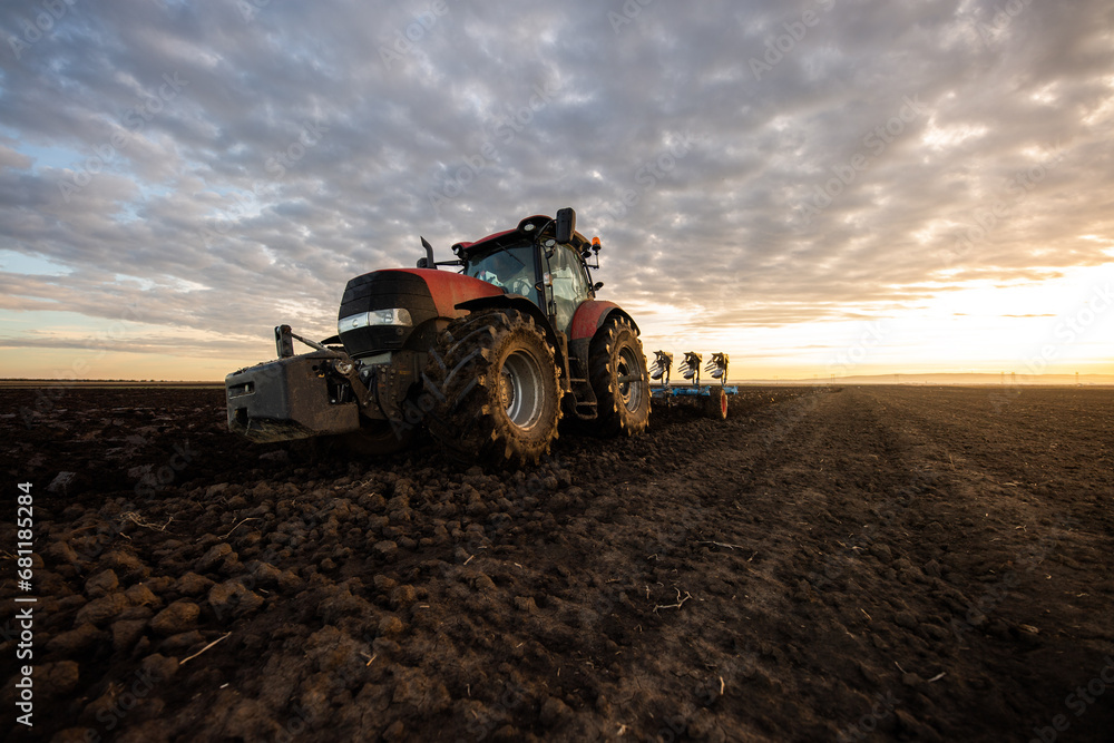 Obraz premium Tractor on the field during sunset.