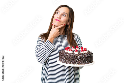 Middle age caucasian woman holding birthday cake over isolated chroma key background having doubts