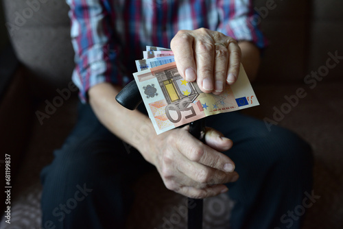 The hands of an old man holding money, euros. Close-up. Poverty, low incomes, austerity in old age, social problems.