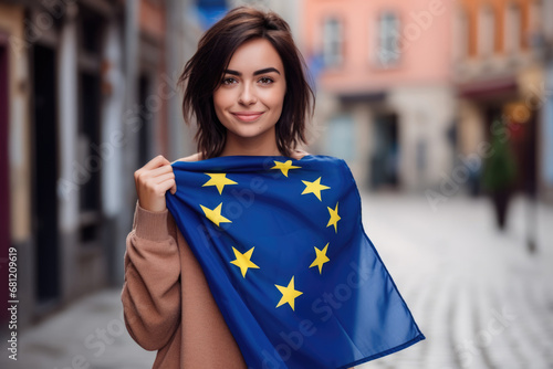 adult caucasian woman standing in the street with an European Union flag, looking happy at the camera.
