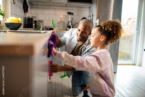 Father and daughter cleaning kitchen photo