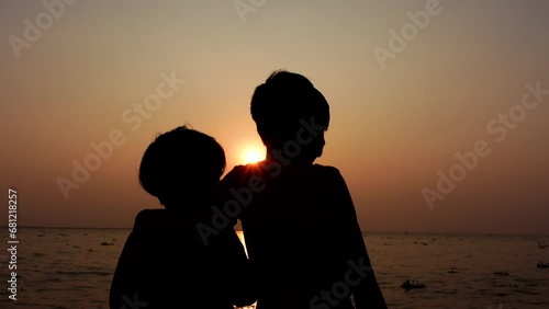 Two children are standing on the river bank at sunset enjoying the evening river view. Silhouette views two kids having fun in the evening time. Two Brothers in Holiday conceptual 4k video. photo
