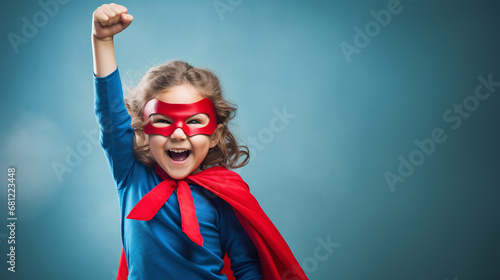 little superhero girl throws up his fists and rejoices in his success photo
