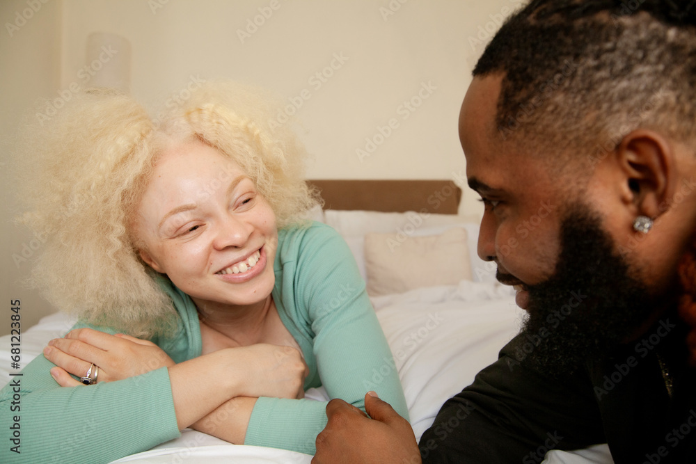 Obraz premium Young woman with albinism smiling at husband on their bed