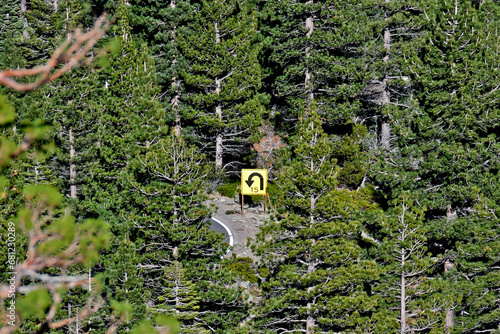 Distant view to 15 MPH warning sign on hairpin turn in conifer forest, Highway 4, Ebbetts Pass road, California  photo