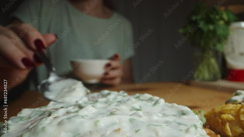 Close-up of the woman spreading mayonnaise and parsley sauce on the chicken patties for the burger. Close-up of the woman spreading mayonnaise and parsley sauce on the chicken patties for the burger.