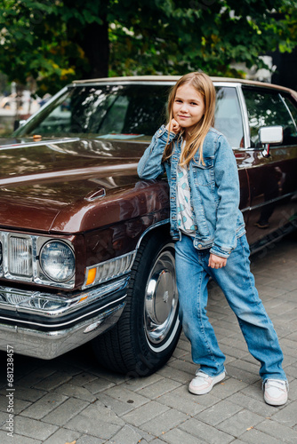 Teenage girl in denim clothes by vintage brown car.