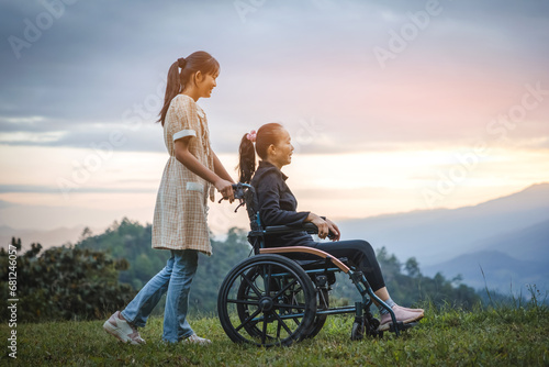 Happy young mother in wheelchair with daughter in spring nature at sunset. photo