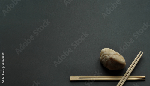 Japanese bamboo chopsticks and light stone on dark gray background. Minimalism, one corner composition, wide copy space. No people photo