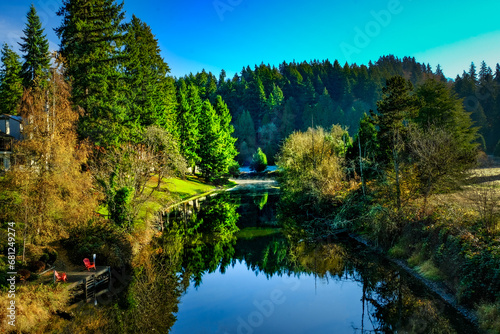 A crisp fall morning on the Sammamish River, with colorful trees and the blue sky reflected in the still water.