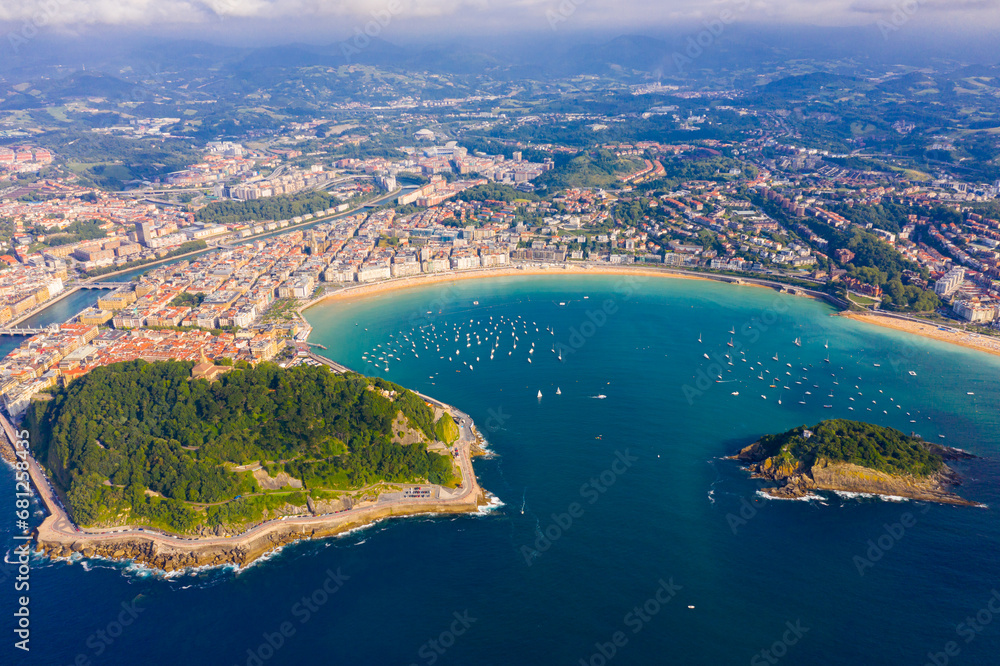 Obraz premium Picturesque aerial view of turquois water of La Concha Bay of San Sebastian with Santa Clara Island and moored pleasure yachts, Spain..