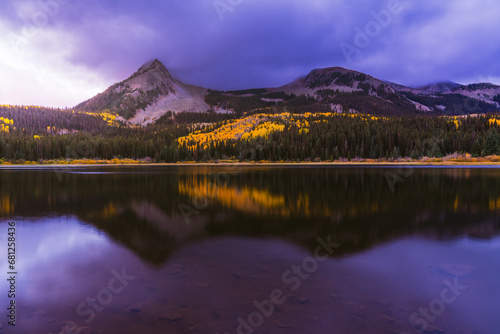 Beautiful purple Sunrise over reflective mirror Lost Lake Colorado in Autumn with yellow Aspen trees and snow covered mountains.  photo