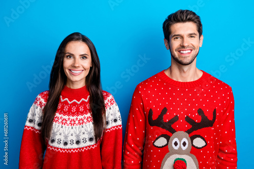 Photo portrait of pretty young lovers toothy smile wear x-mas ornament red sweaters isolated on blue color background
